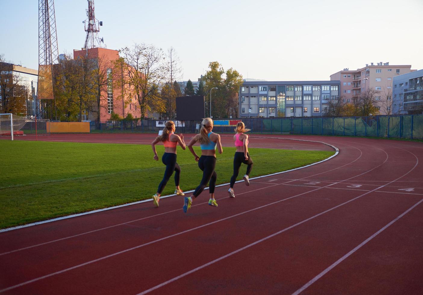 grupo de mujeres atletas corriendo en la pista de carreras de atletismo foto