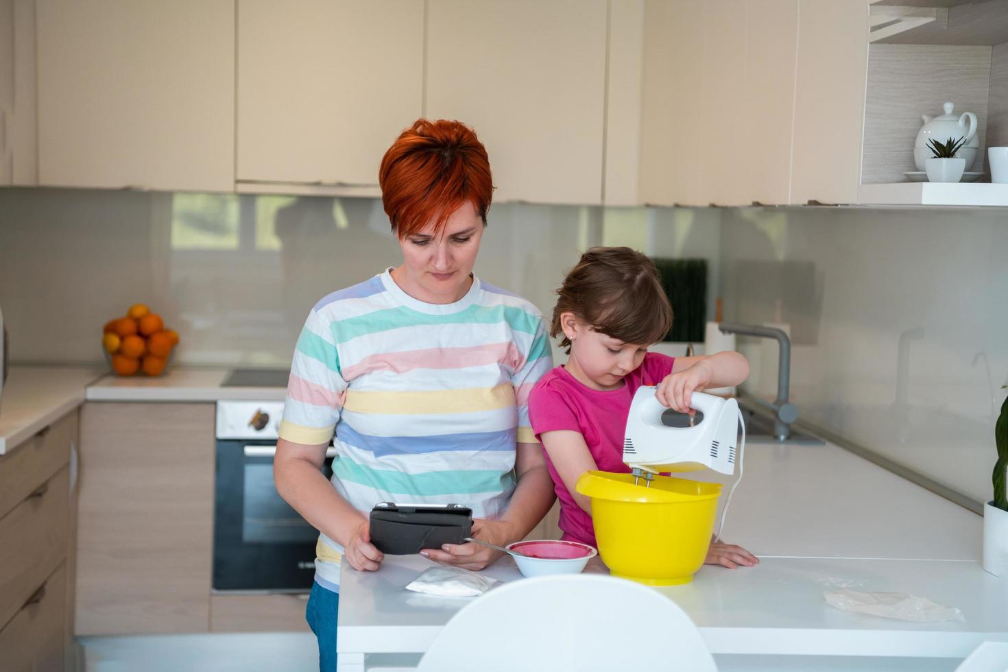 little girl and mom making tastz cake in kithen family having fun at home photo