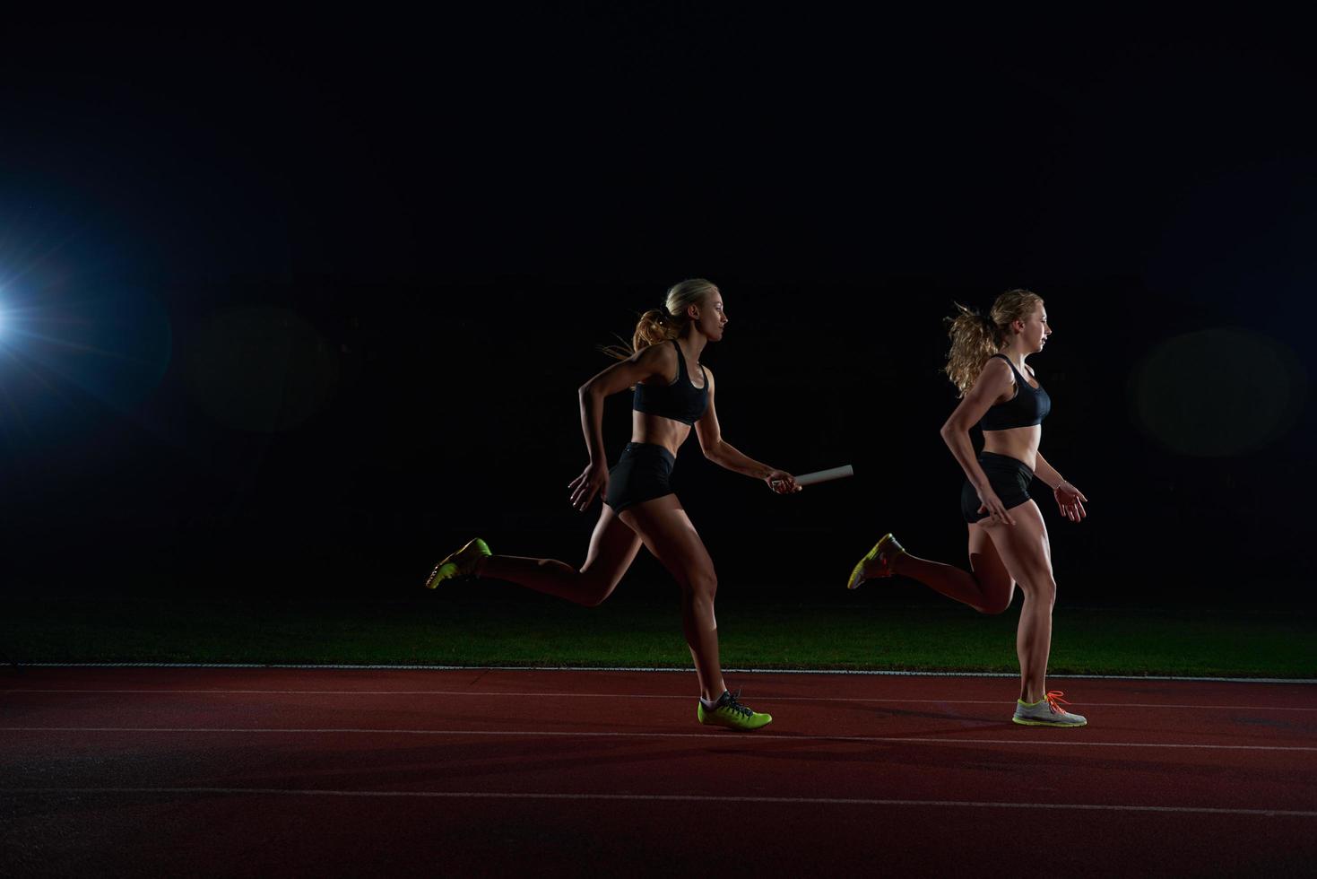 athletic runners passing baton in relay race photo