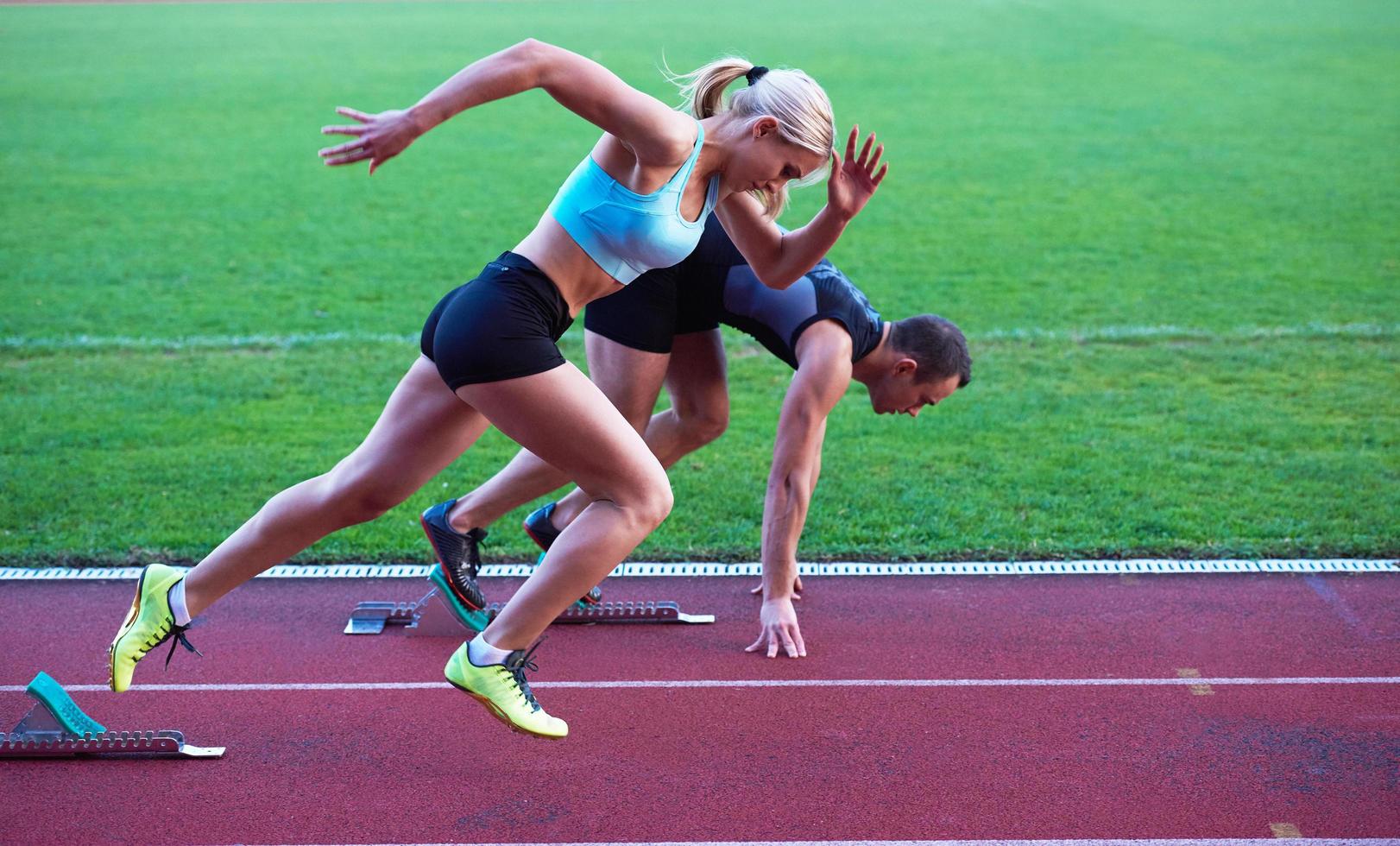 woman group  running on athletics race track from start photo