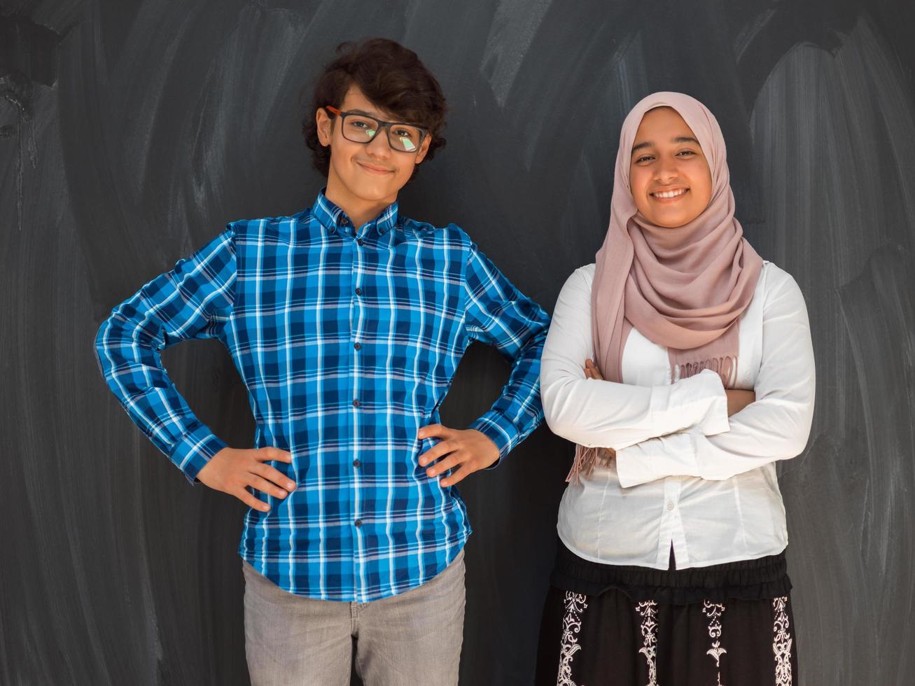 A portrait of a group of Arab teenagers with crossed arms standing in front of a school board . The concept of modern and successful education photo