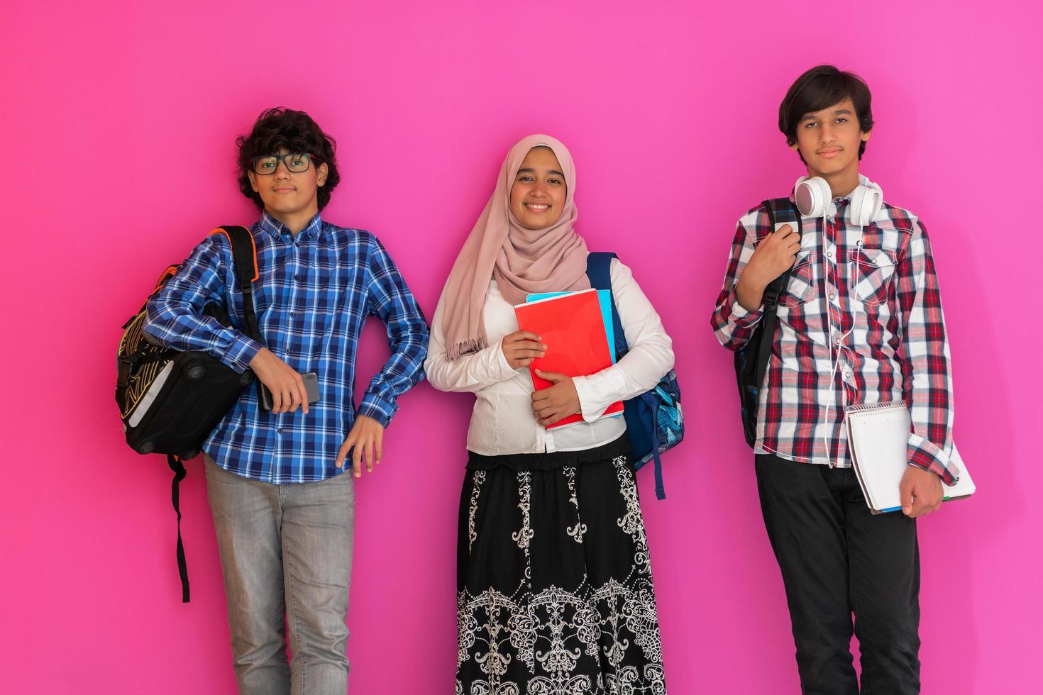 A group of Arab teenagers, a student team walking forward into the future and back to school the concept of a pink background. The concept of successful education for young people. Selective focus photo