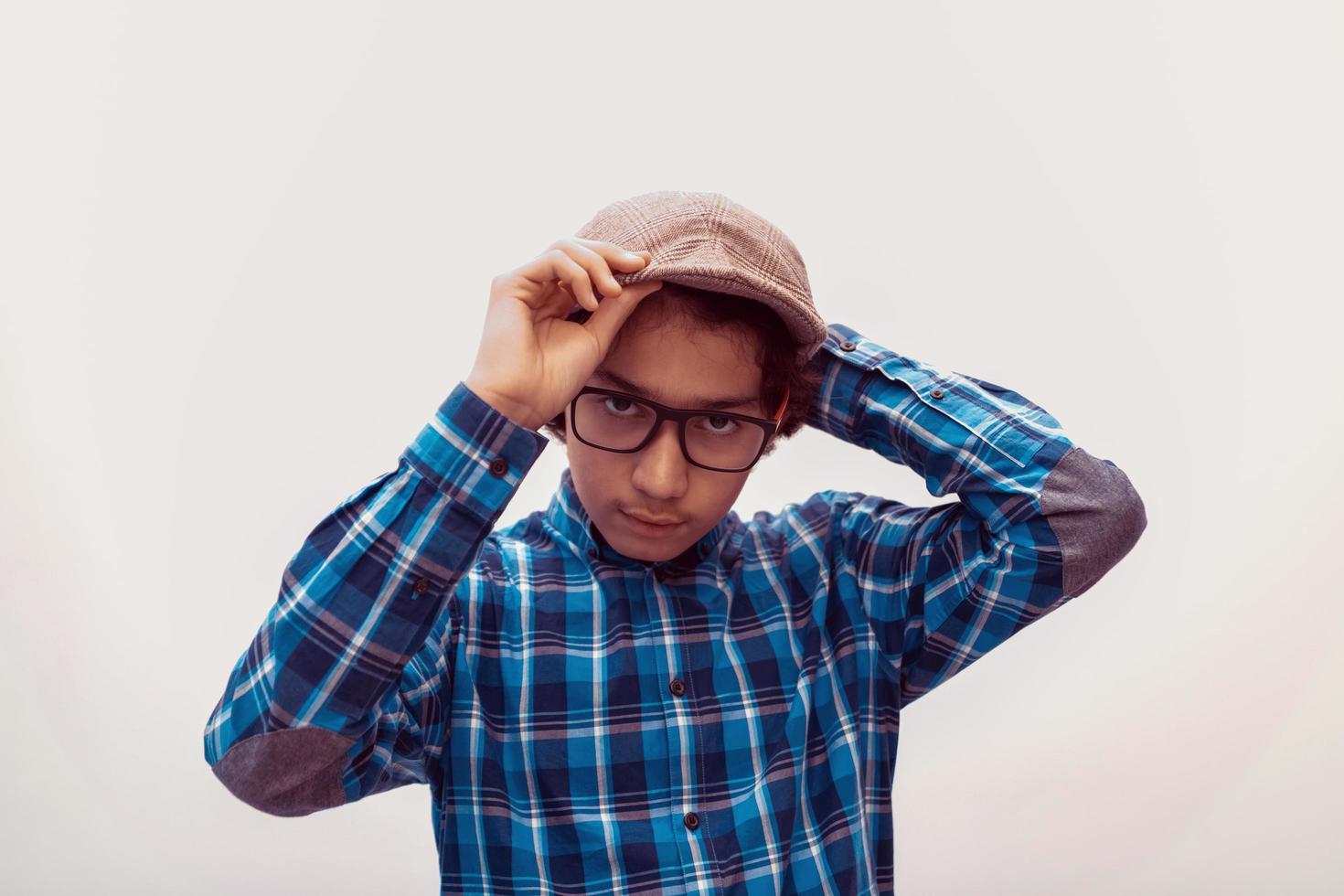 portrait of smart looking arab teenager with glasses wearing a hat in casual school look isolated on white copy space photo