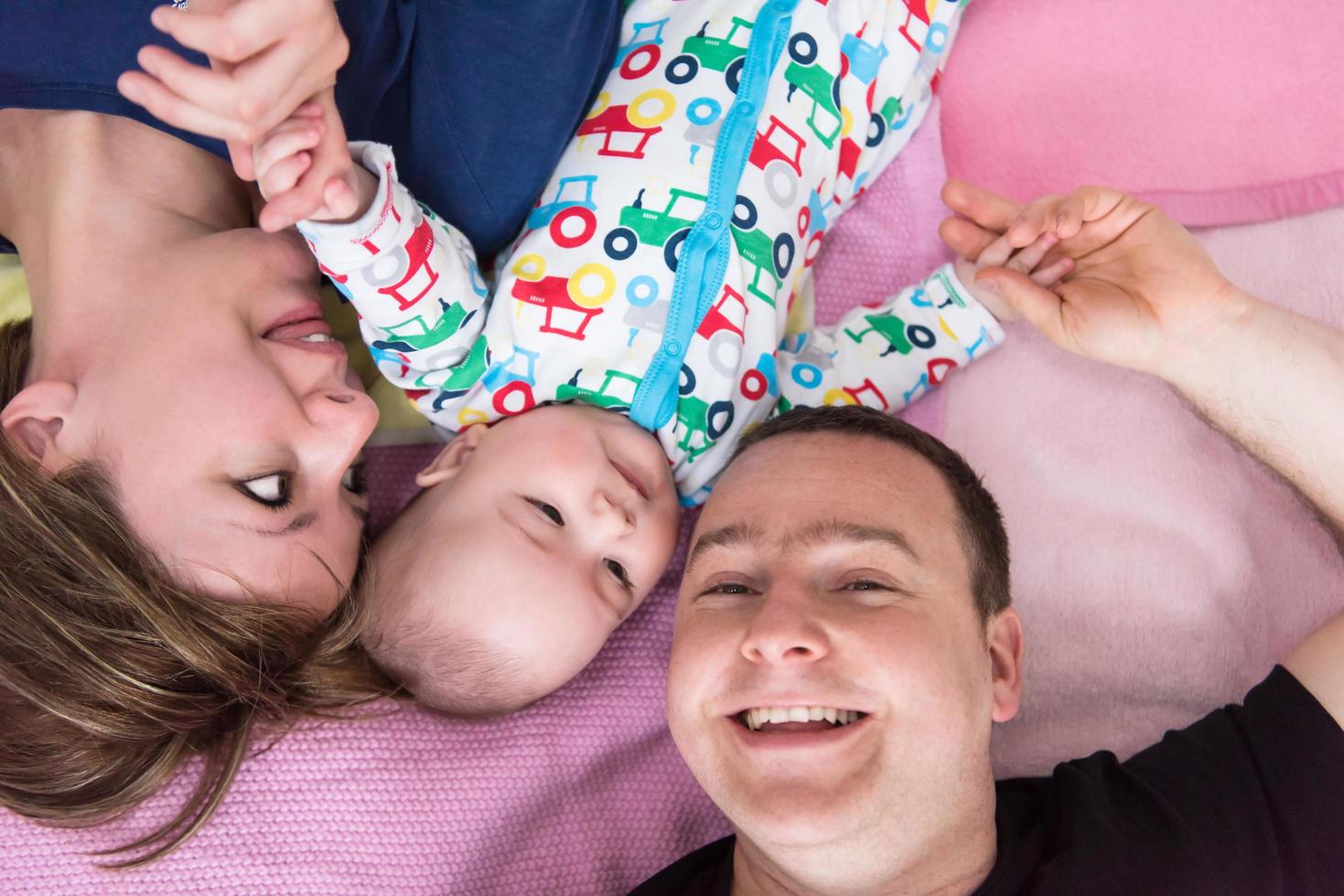 Top view of smiling young couple lying with their baby photo