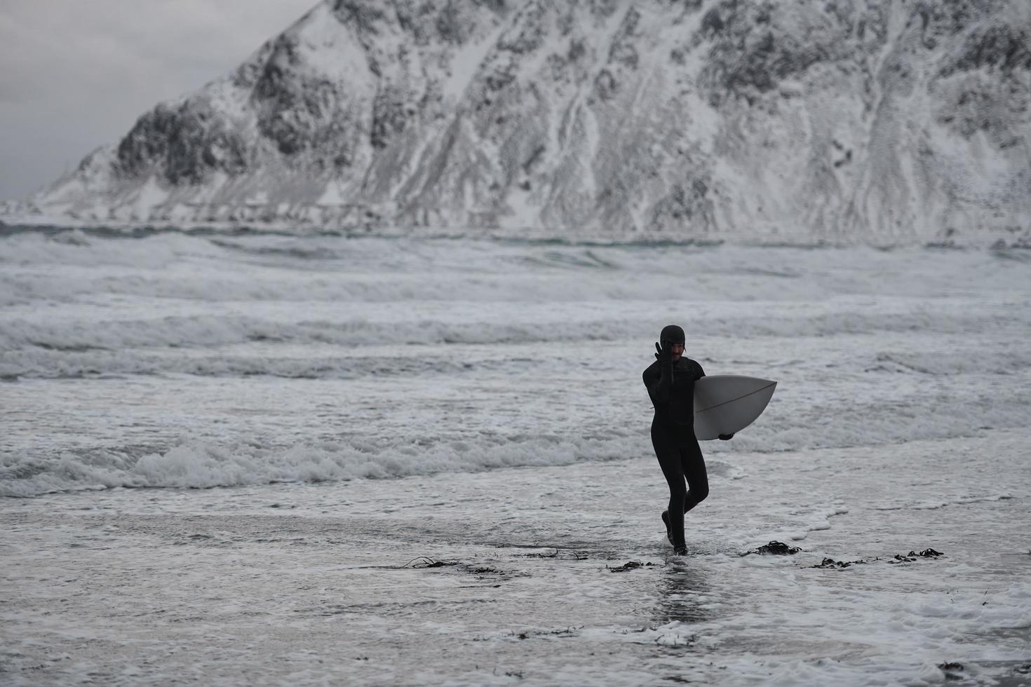 surfista ártico yendo por la playa después de surfear foto