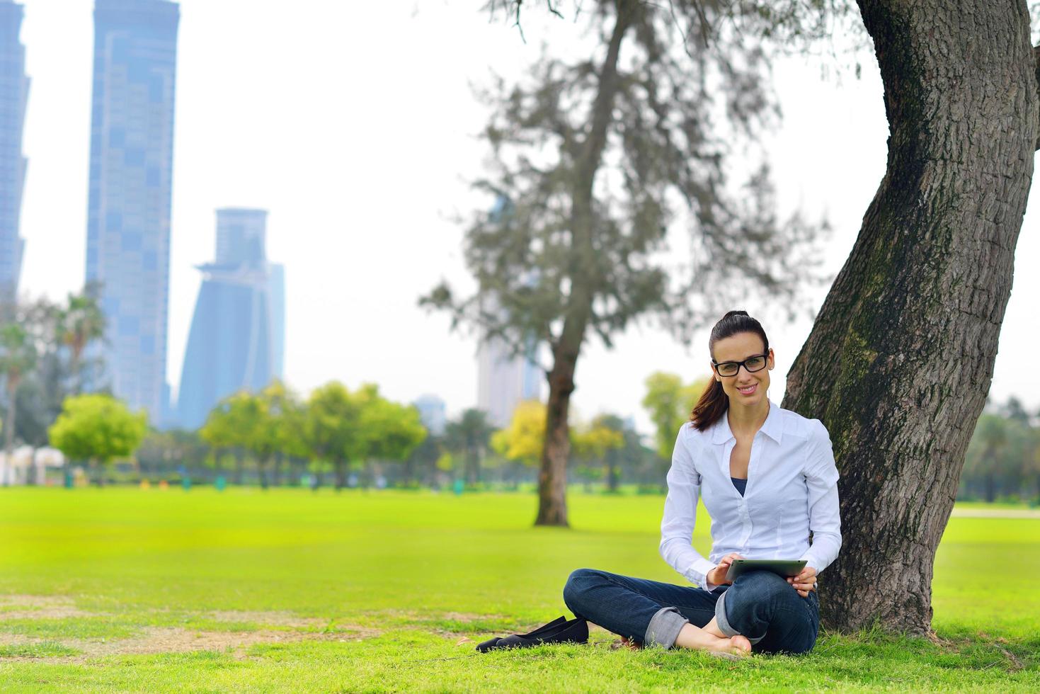 Beautiful young woman with  tablet in park photo