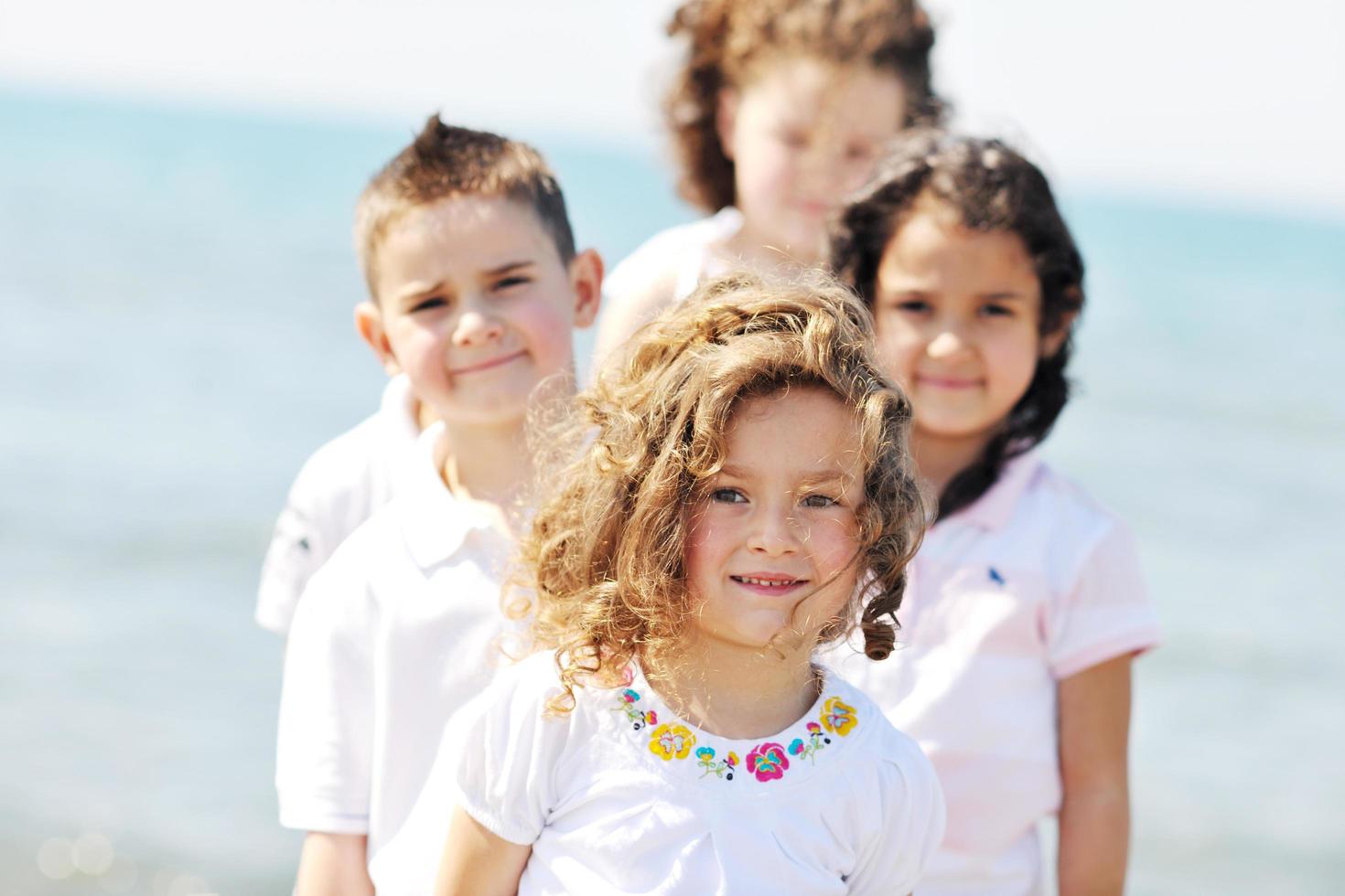 Grupo de niños felices jugando en la playa foto