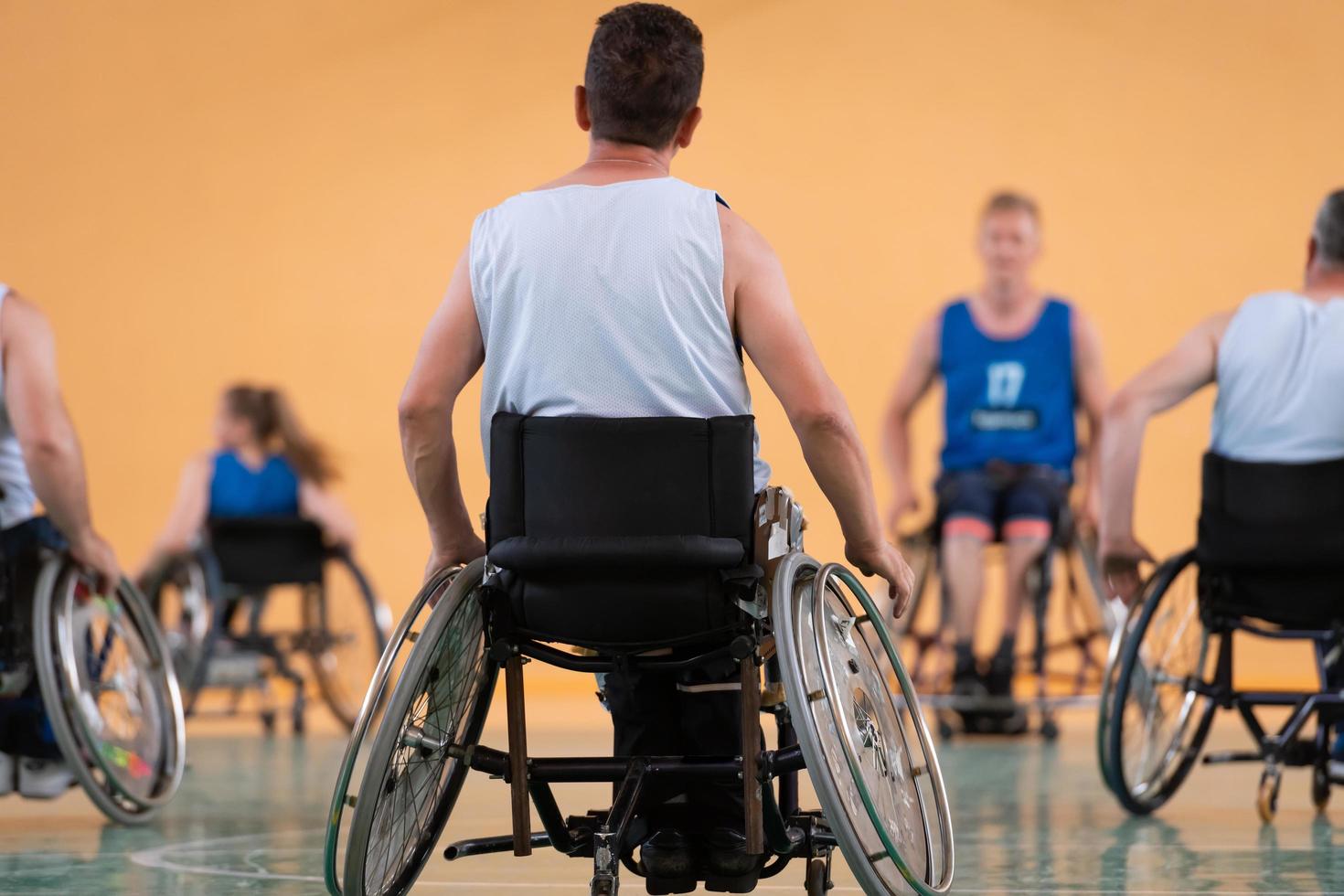 Close up photo of wheelchairs and handicapped war veterans playing basketball on the court