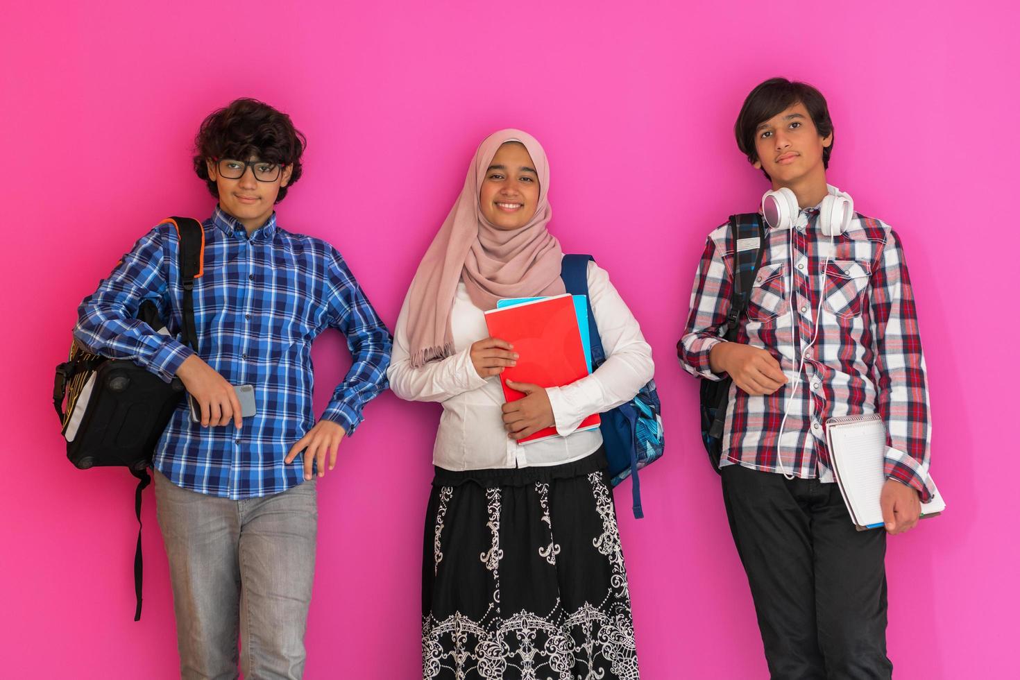 A group of Arab teenagers, a student team walking forward into the future and back to school the concept of a pink background. The concept of successful education for young people. Selective focus photo