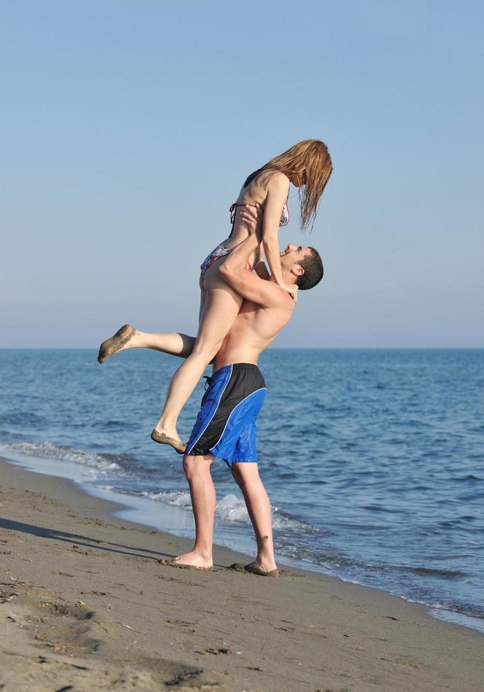 feliz pareja joven tiene tiempo romántico en la playa foto