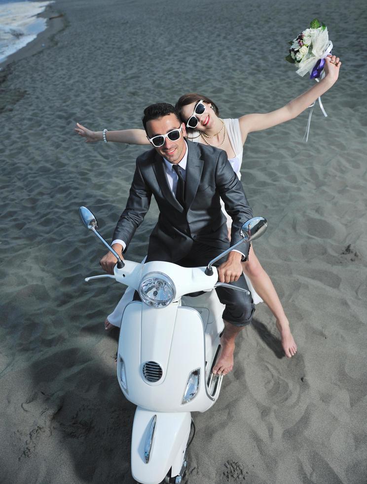 pareja de recién casados en la playa paseo scooter blanco foto