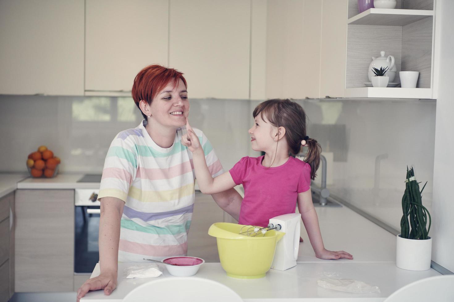 madre e hija jugando y preparando masa en la cocina. foto