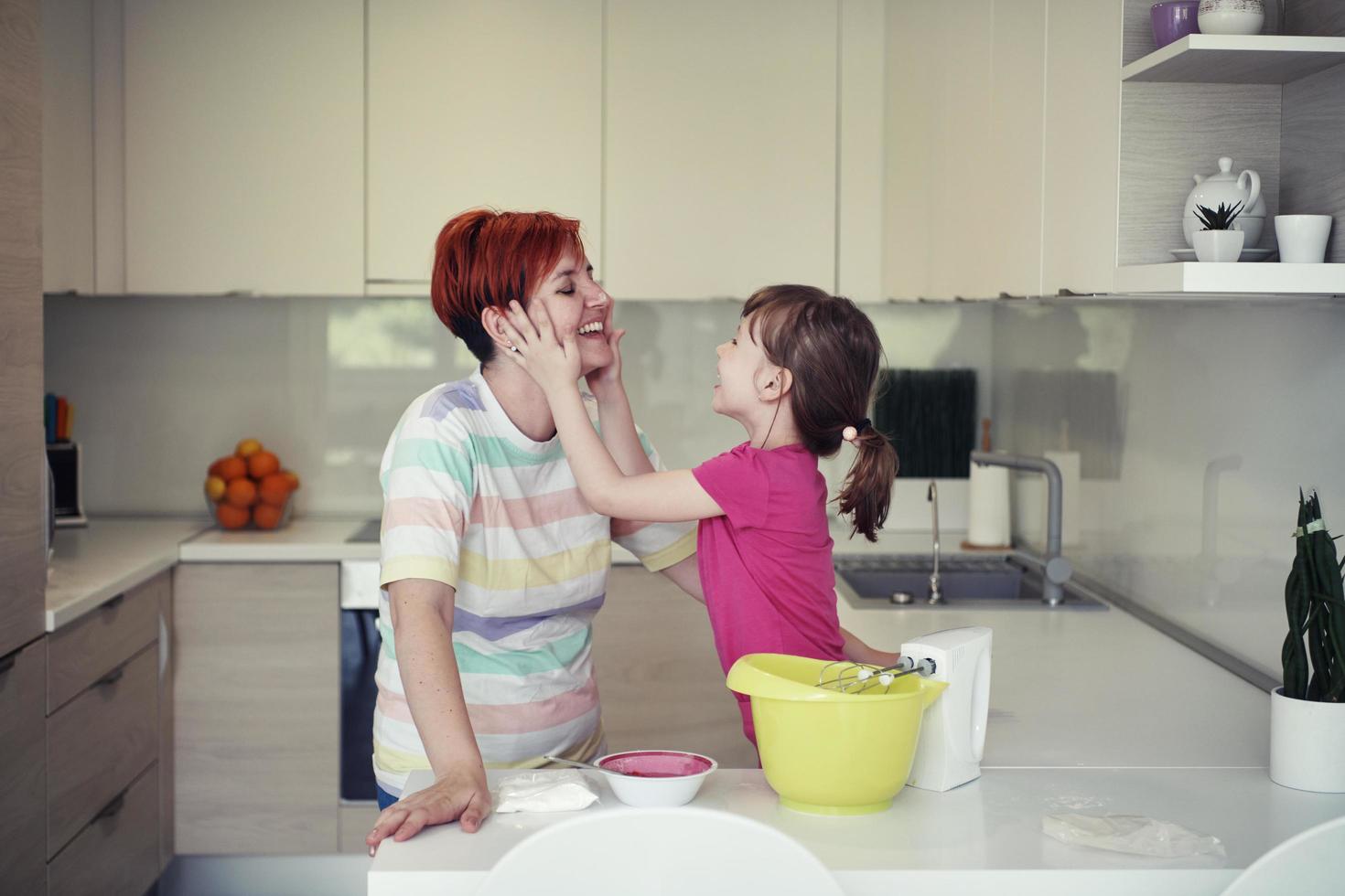 Mother and daughter playing and preparing dough in the kitchen. photo