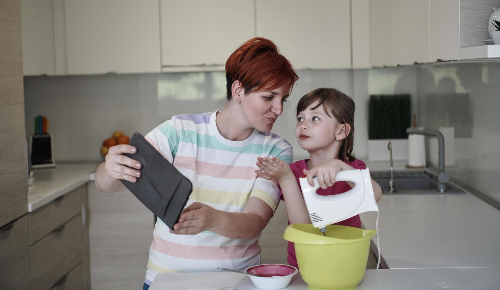 Mother and daughter playing and preparing dough in the kitchen. photo