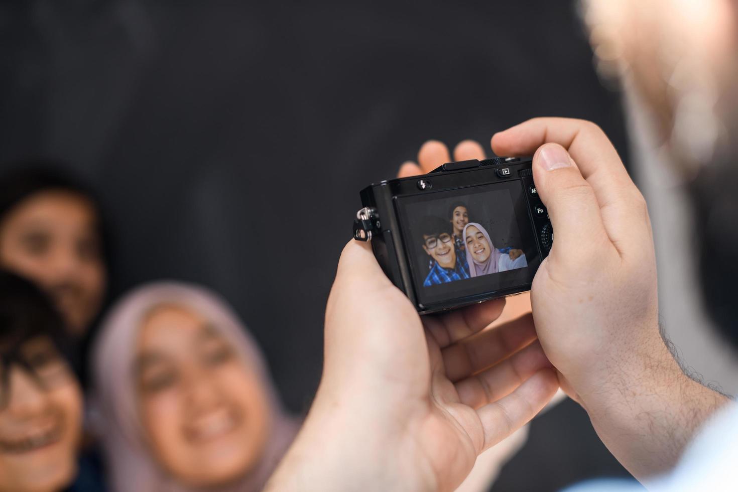 A father with a camera photographs his children as they pose with a smile on their face photo