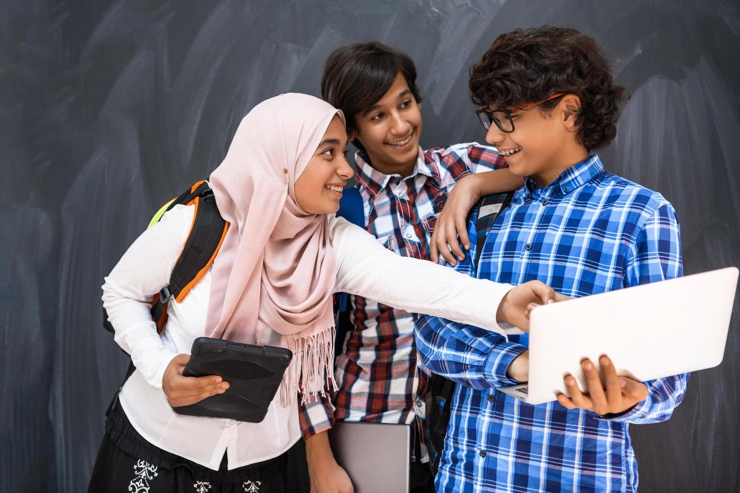 equipo de adolescentes árabes, grupo de estudiantes trabajando juntos en el concepto de educación en el aula en línea de computadoras portátiles y tabletas foto