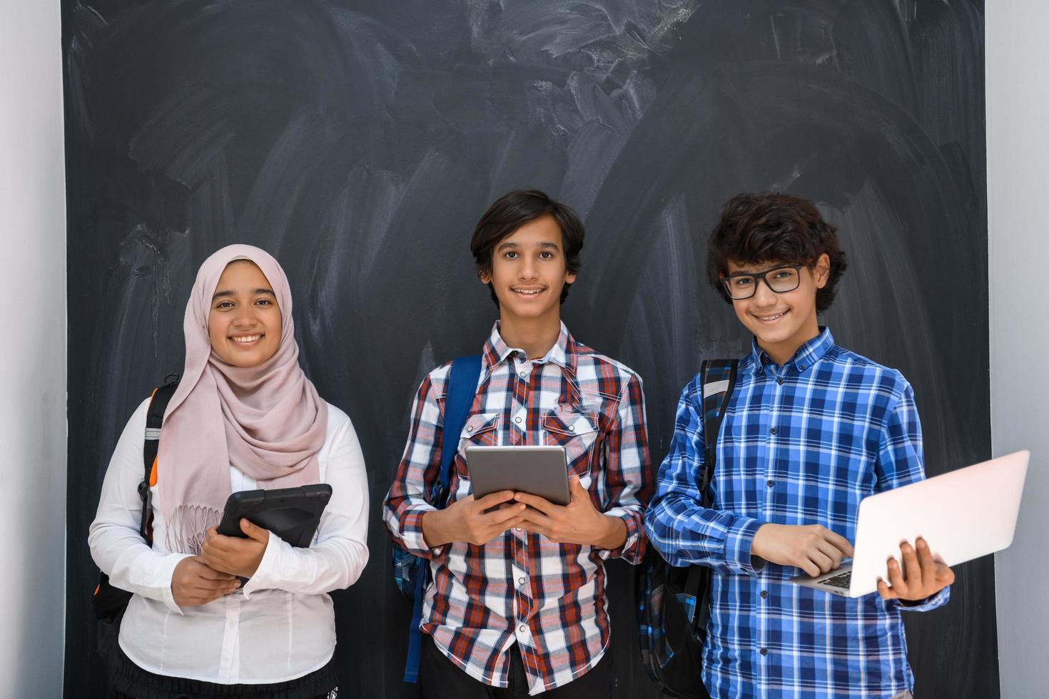 equipo de adolescentes árabes, grupo de estudiantes trabajando juntos en el concepto de educación en el aula en línea de computadoras portátiles y tabletas foto