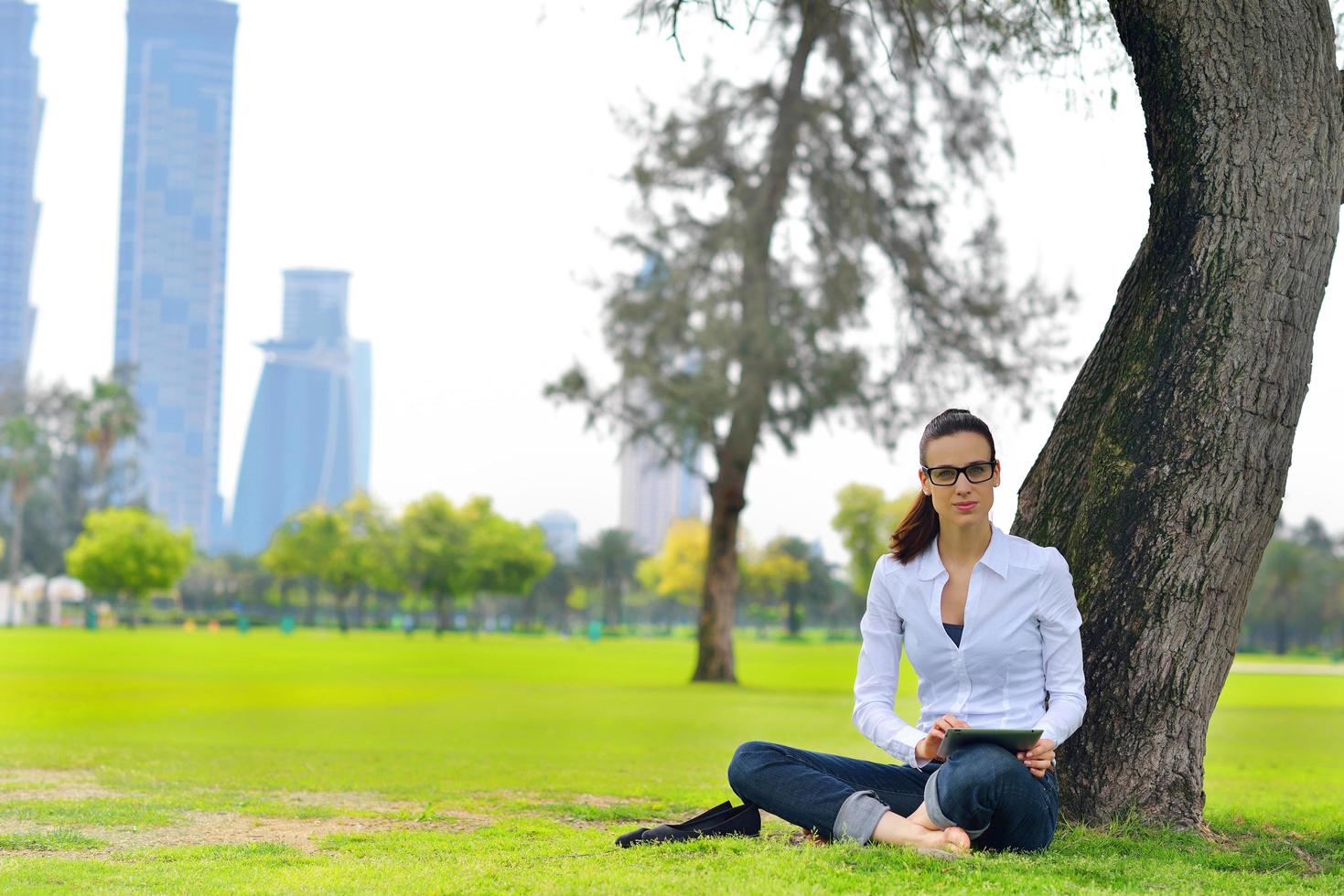 Beautiful young woman with  tablet in park photo