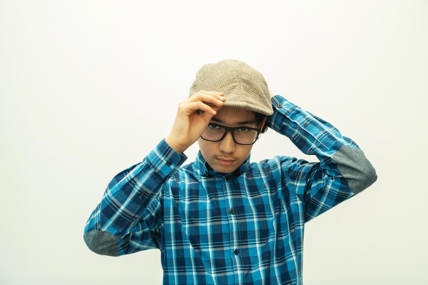 portrait of smart looking arab teenager with glasses wearing a hat in casual school look isolated on white copy space photo