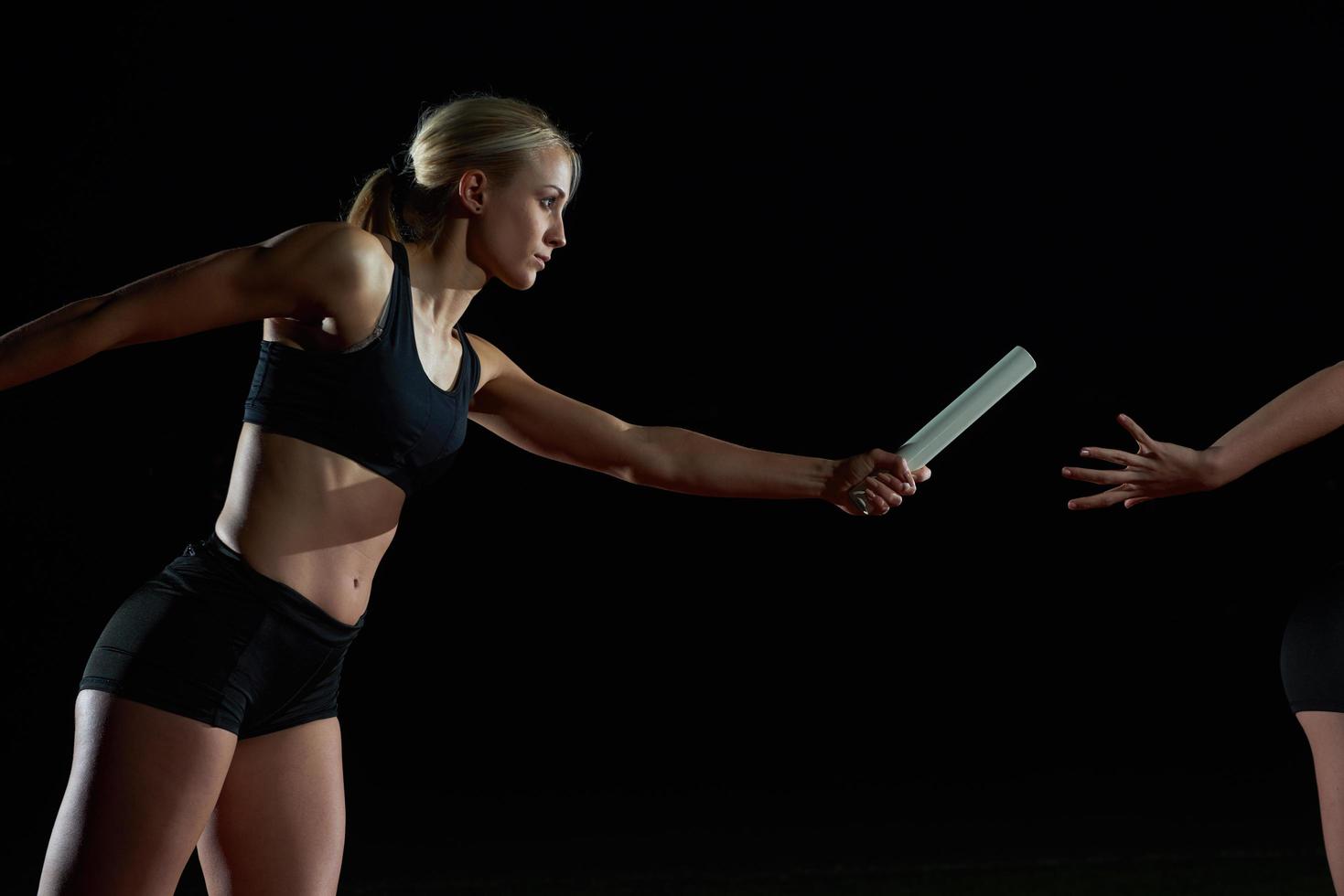 athletic runners passing baton in relay race photo