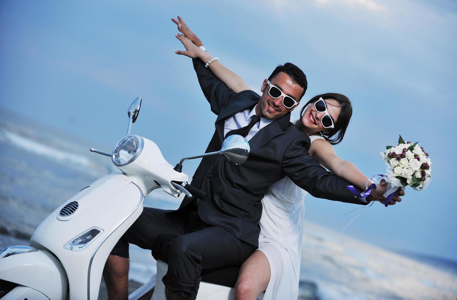 just married couple on the beach ride white scooter photo