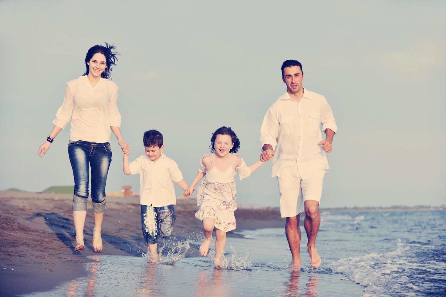 familia joven feliz divertirse en la playa foto