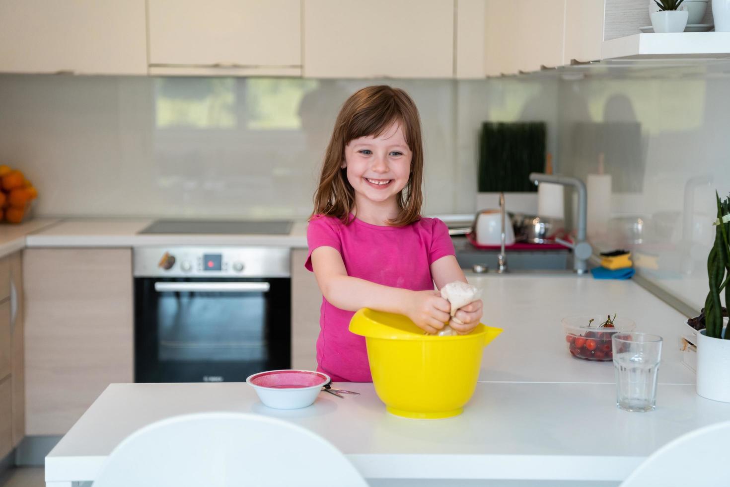 la niña prepara masa en una batidora sumergible y se lame los dedos. los electrodomésticos modernos son convenientes y simples incluso para los niños. un pasatiempo de cocinar. enfoque selectivo foto