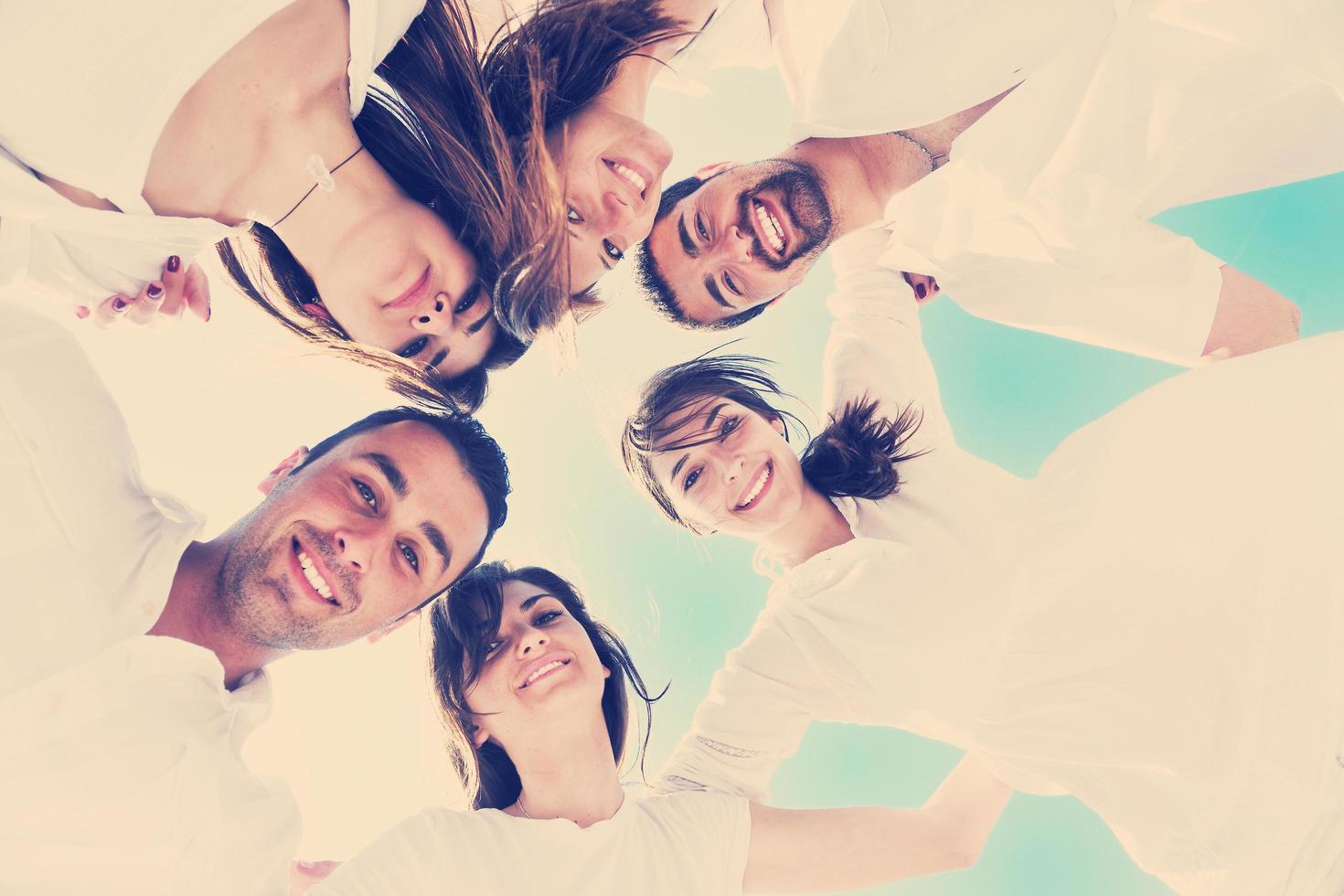 Group of happy young people in circle at beach photo