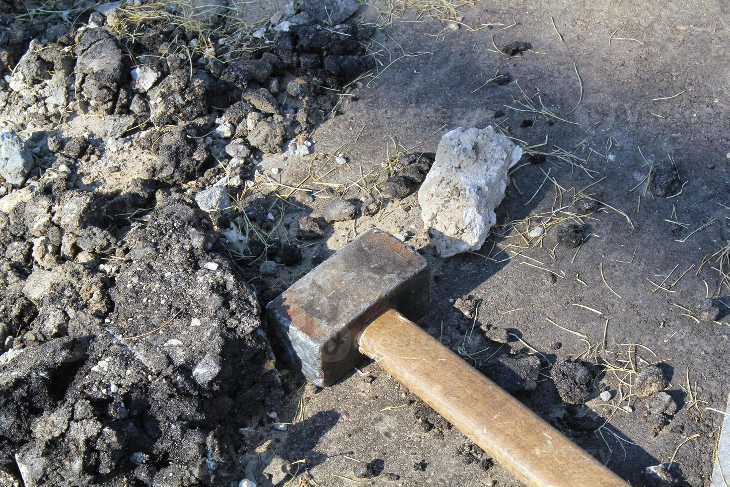 Close-up of big metal steel sledge hammer with wooden handle on cracking old pavement after road breaking. Hard work technical equipment on construction site. Industry tools. Work labor concept photo