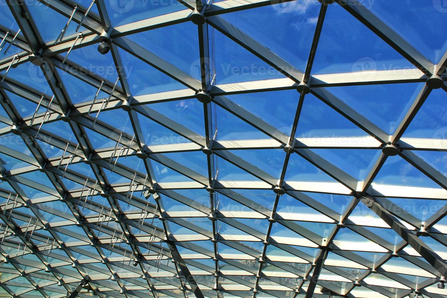 Transparent glass dome roof of modern design style pavilion building with geometric metal construction pattern. View of blue sky and clouds. Abstract structure triangle high-tech architecture window. photo