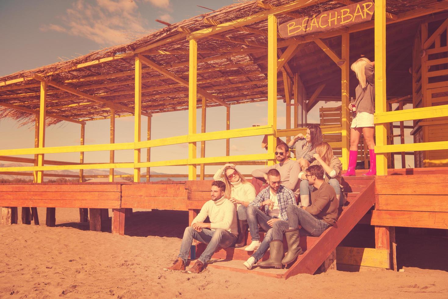 Group of friends having fun on autumn day at beach photo