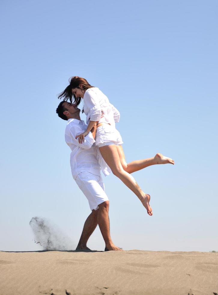 feliz pareja joven divertirse en la playa foto