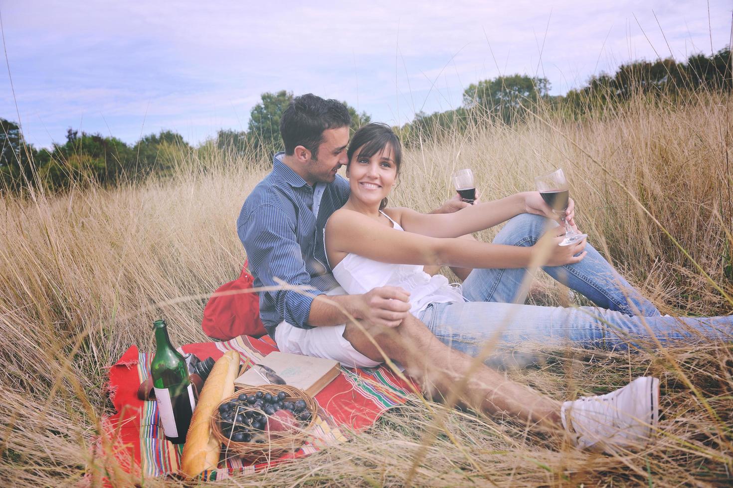 happy couple enjoying countryside picnic in long grass photo