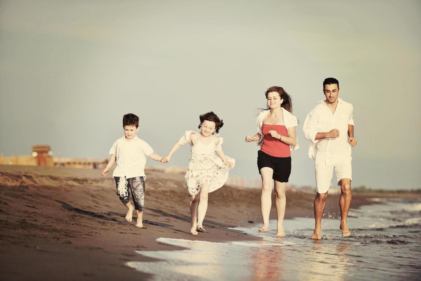 familia joven feliz divertirse en la playa foto