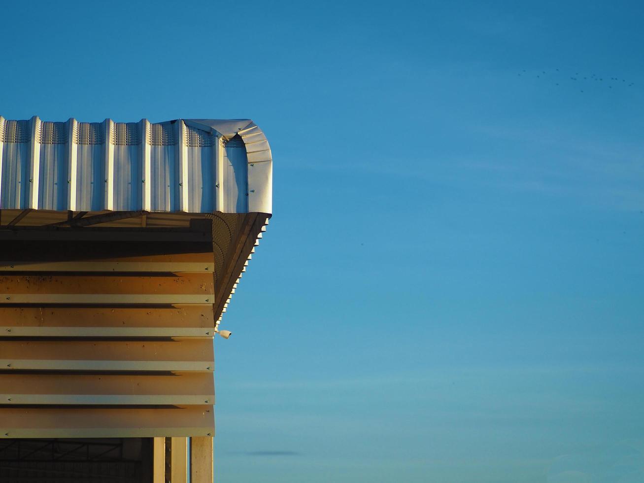 The metal sheet roof of the factory receives sunlight from the morning sun. On a background that is blue sky photo