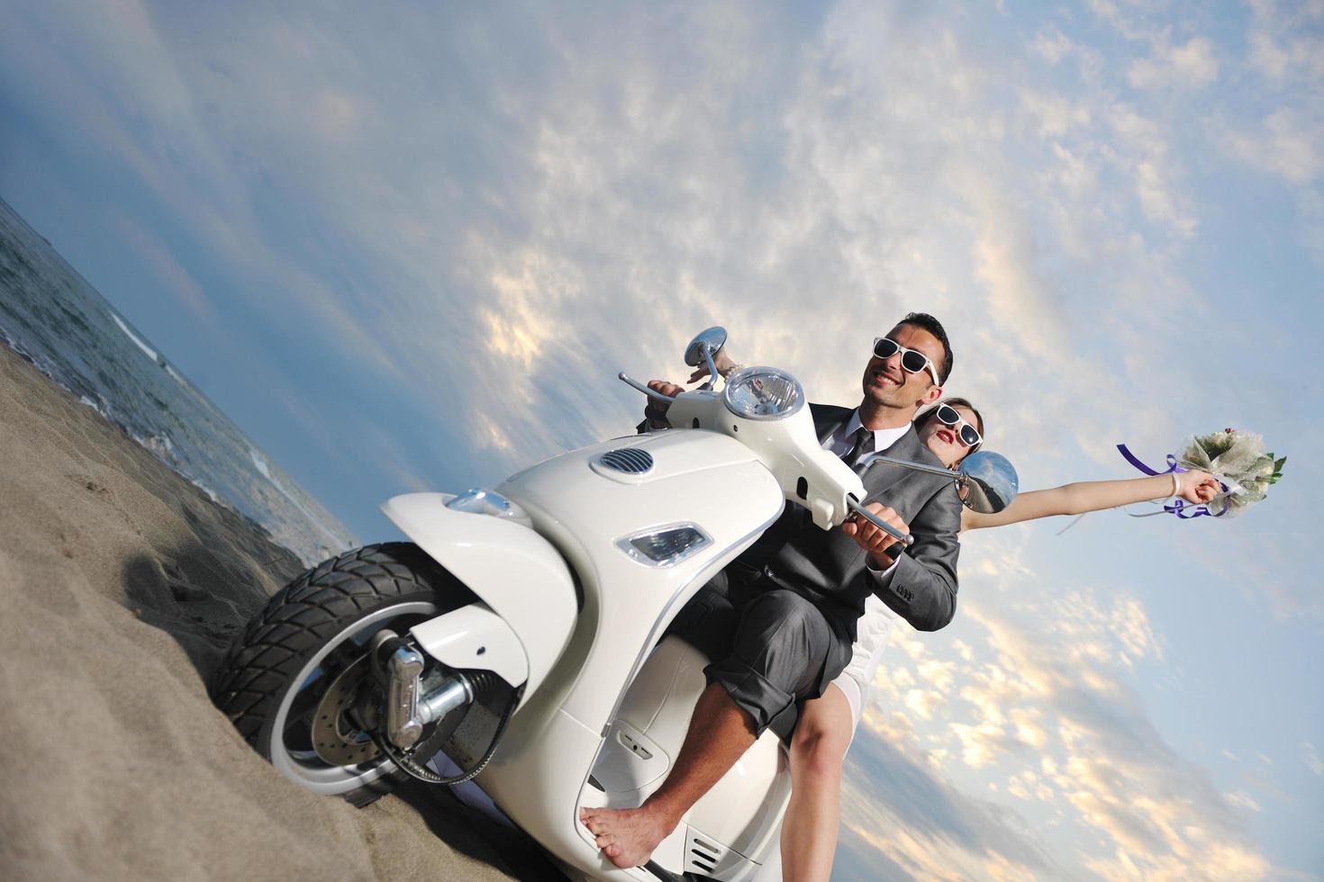 just married couple on the beach ride white scooter photo