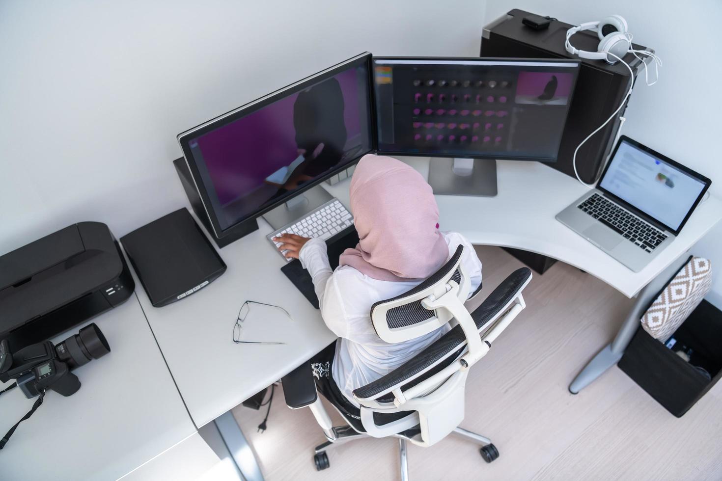 profesional creativa árabe femenina que trabaja en la oficina en casa en una computadora de escritorio con vista superior de monitor de pantalla dual. enfoque selectivo foto