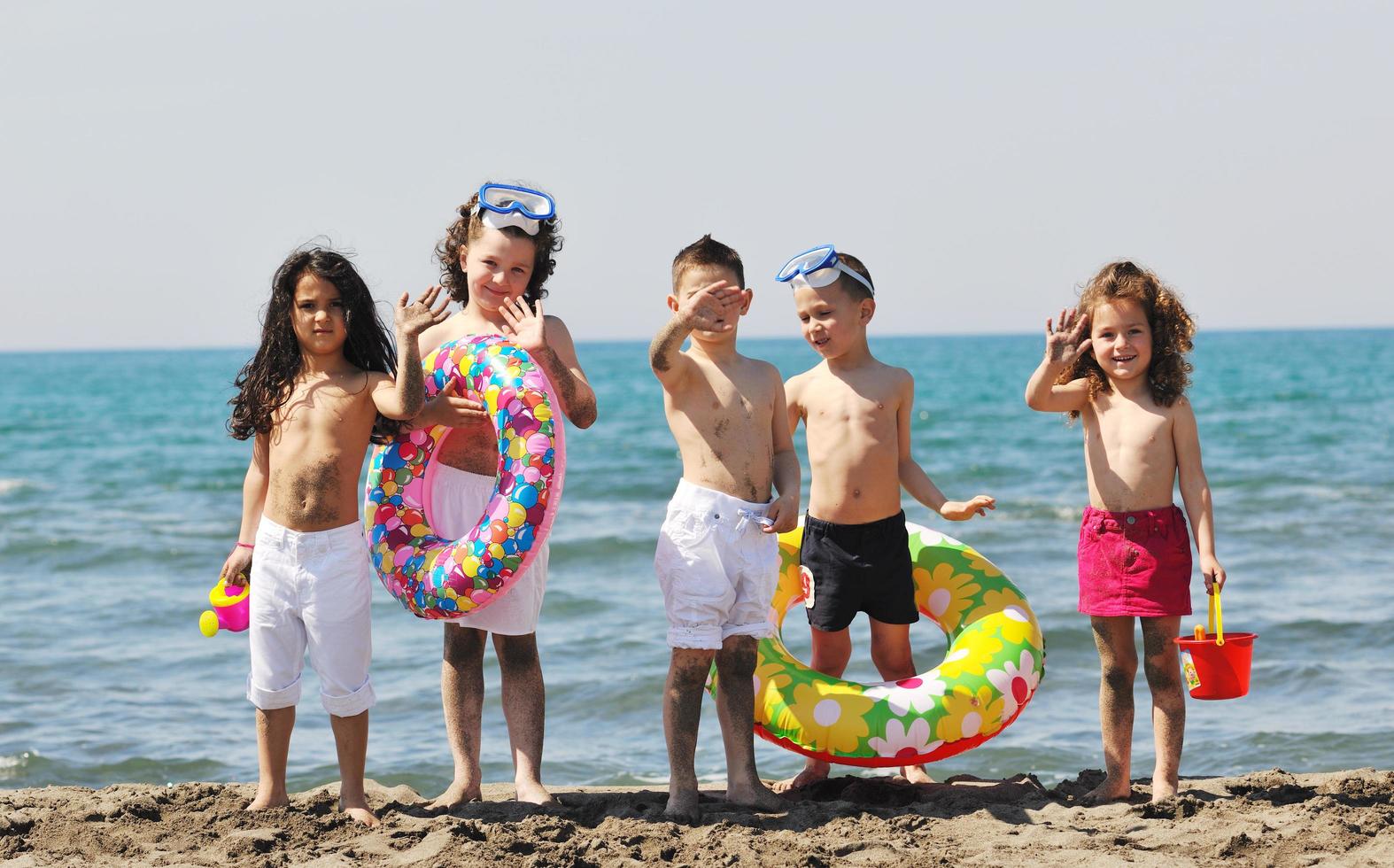 grupo infantil divertirse y jugar con juguetes de playa foto