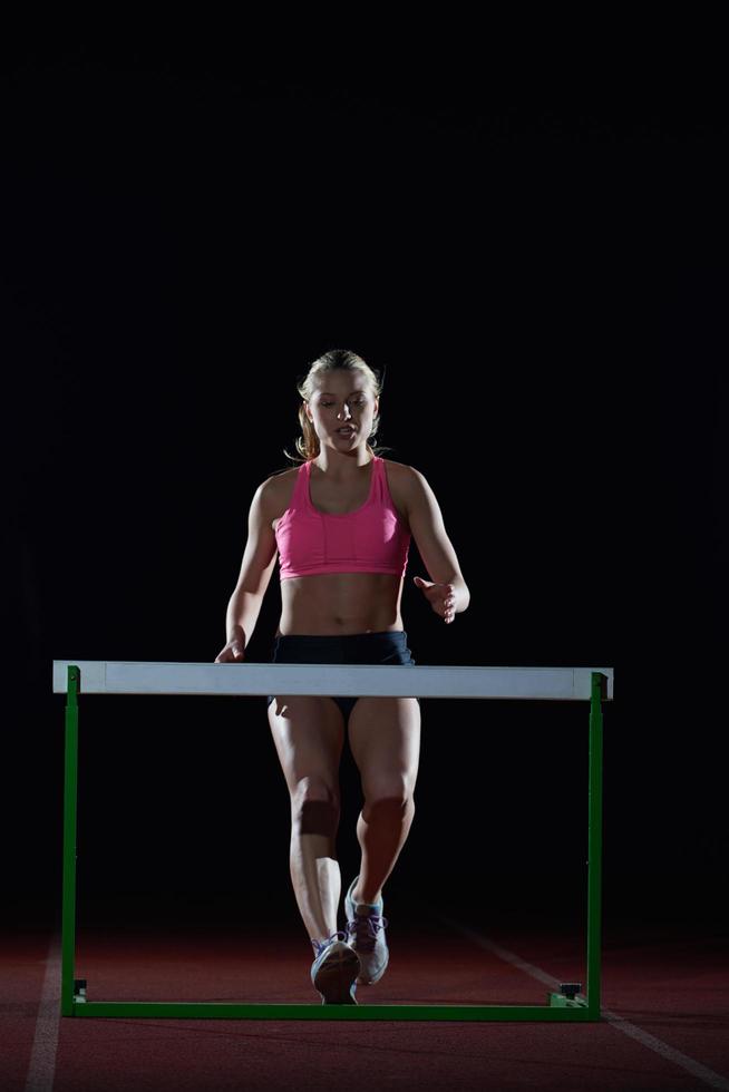 woman athlete jumping over a hurdles photo