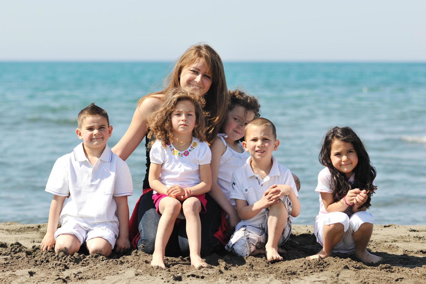 retrato de grupo de niños con profesor en la playa foto