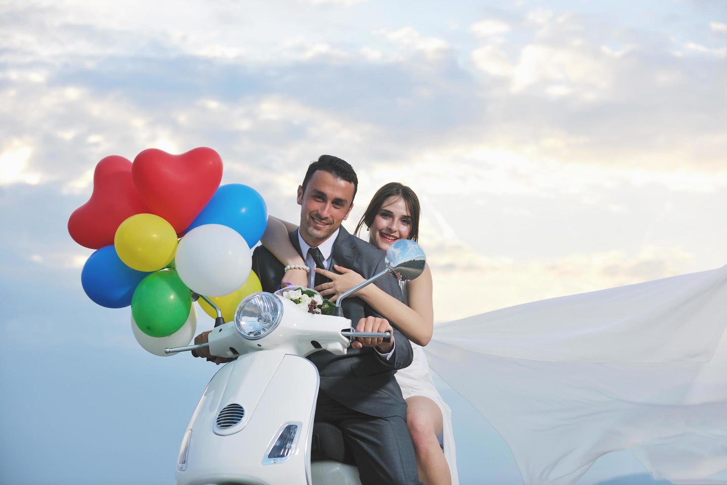 pareja de recién casados en la playa paseo scooter blanco foto