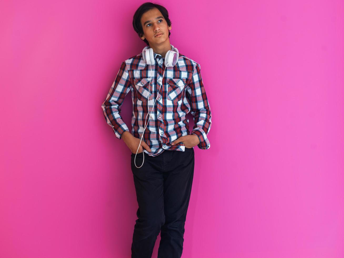 Arabic Teenage Boy Wearing Headphones And Listening To Music pink background photo