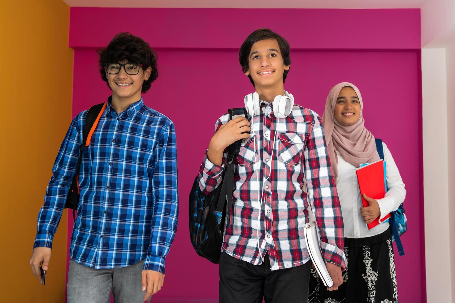 A group of Arab teenagers, a student team walking forward into the future and back to school the concept of a pink background. The concept of successful education for young people. Selective focus photo