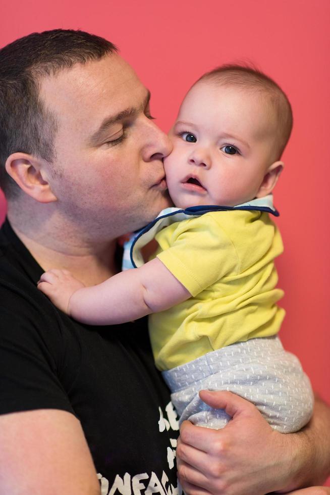 retrato de un joven padre feliz sosteniendo a un bebé aislado en rojo foto