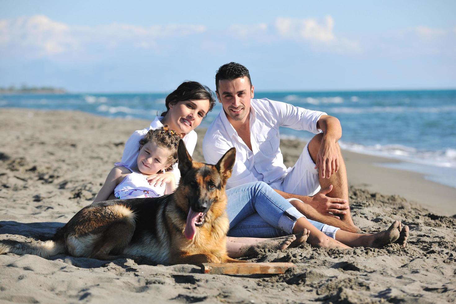 happy family playing with dog on beach photo