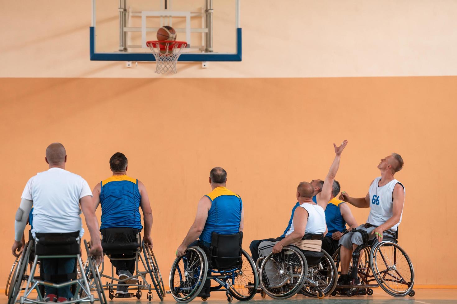 Disabled War veterans mixed race and age basketball teams in wheelchairs playing a training match in a sports gym hall. Handicapped people rehabilitation and inclusion concept photo