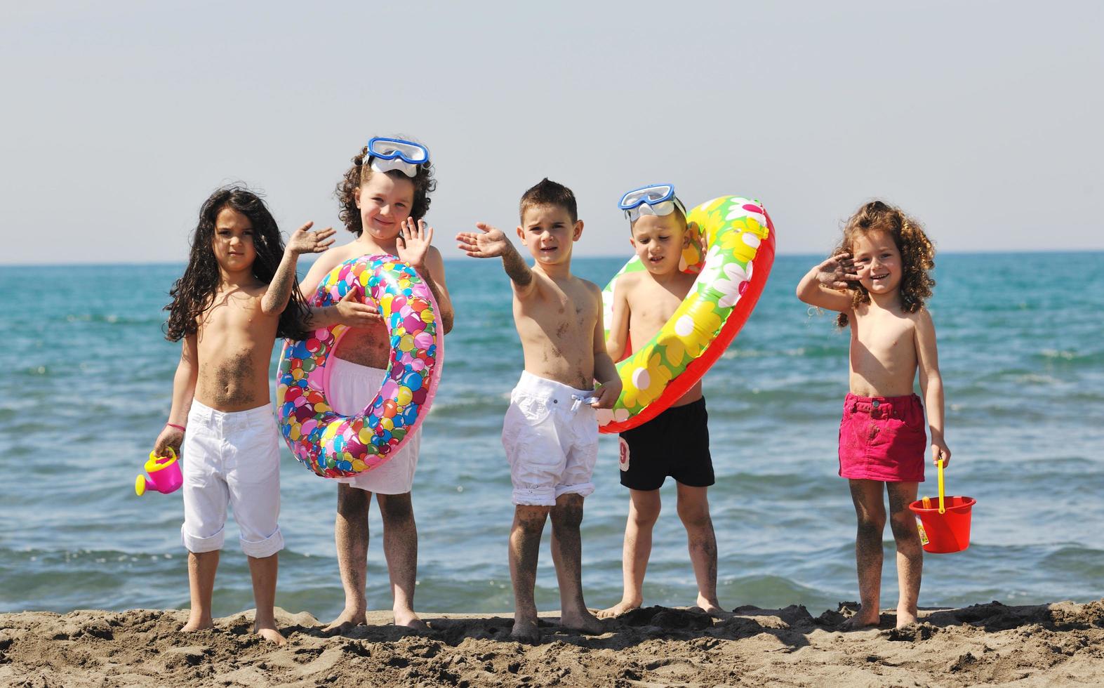 grupo infantil divertirse y jugar con juguetes de playa foto