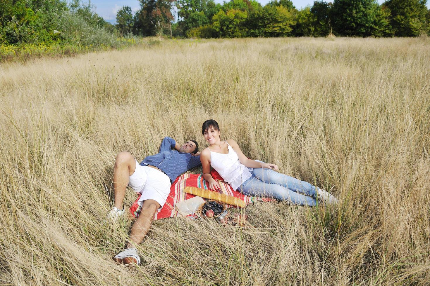 happy couple enjoying countryside picnic in long grass photo