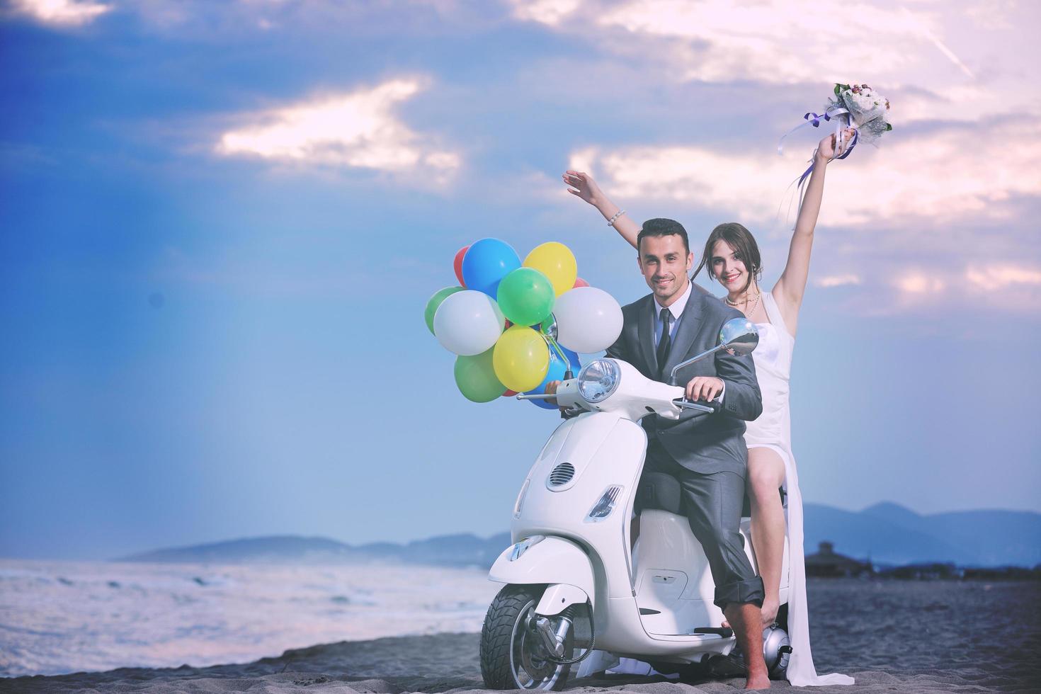 just married couple on the beach ride white scooter photo