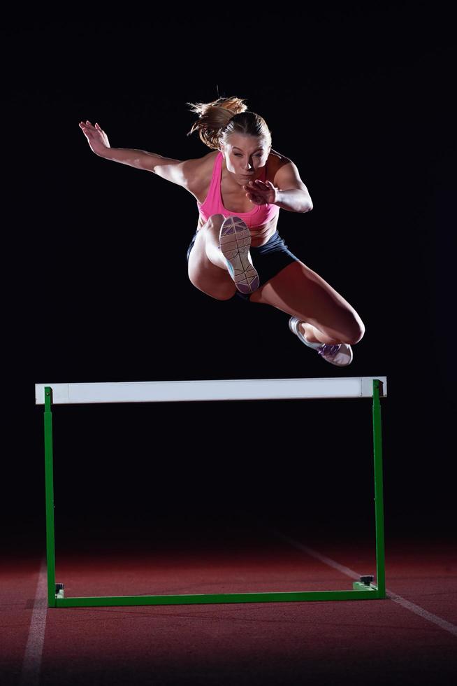 mujer atleta saltando sobre obstáculos foto